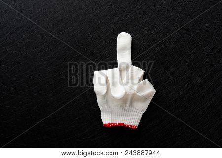An Offensive Gesture Of Middle Finger Up Made By White Glove On Black Background
