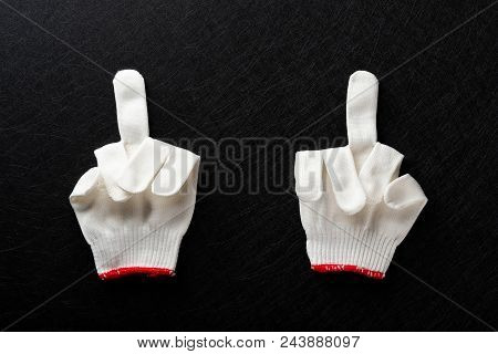 An Offensive Gesture Of Middle Fingers Up Made By White Gloves On Black Background