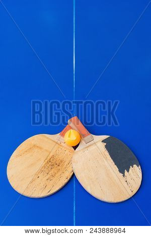 Pair Of Old Pingpong Rackets And A Dented Ball On A Blue Pingpong Table