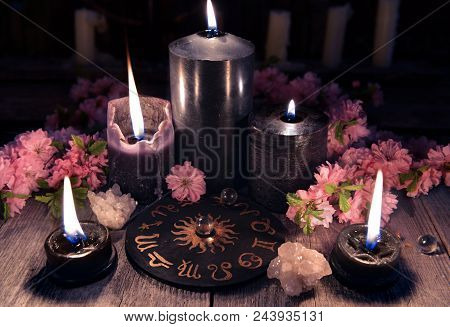 Black Candles And Zodiac Circle With Sakura Flowers On Witch Table. Occult, Esoteric And Divination 