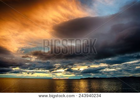 Sunset Over Stormy Clouds Across The Water Reflecting Dark And Looming Dramatic Sky Moody Feeling Of