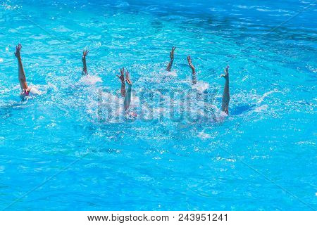 Synchronised Swimming. Beautiful Lean Female Legs In The Water Of A Swimming Pool. Concept Of Beauty