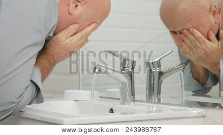 Man In Modern Bathroom Washing Face With Fresh Water In Sink