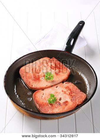 Duas fatias de carne do almoço na panela quente preta