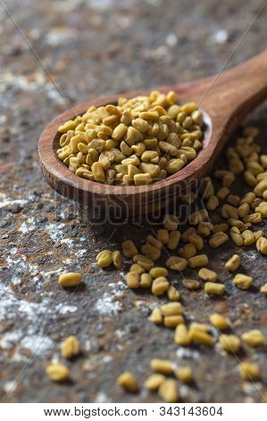 Fenugreek Seeds In Wooden Spoon On Textured Background