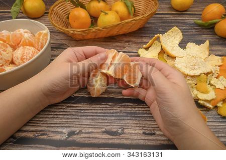 The Girls Hands Are Cleaning Tangerine, Tangerines On A Twig With Green Leaves, Peeled Tangerines In