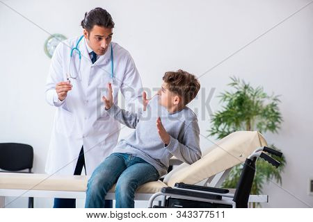 Young male doctor pediatrist and boy in wheel-chair