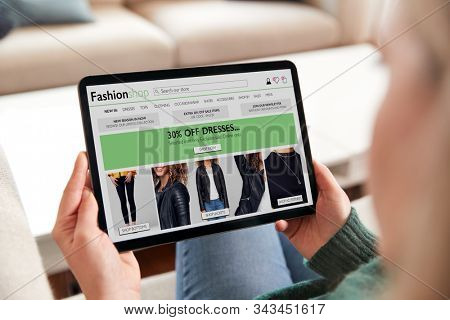 Close Up Of Woman Shopping For Clothes Online At Home Using Digital Tablet App