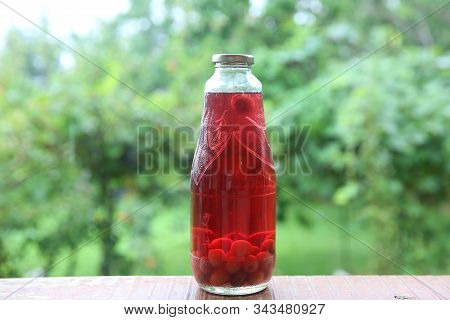 Homemade Jar Of Sliced, Canned Cornelian Cherry On Green Background. Cornelian Cherry Kompot, A Swee