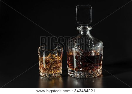 Beautiful View Whiskey Decanter And Glass Of Whiskey With Ice On Black Background. Beautiful Backgro