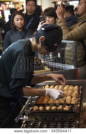 Osaka, Japan- 27 Nov, 2019: Vendor Making Takoyaki On A Takoyaki Pan In Osaka, Japan. Takoyaki Is Fa