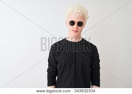 Young albino man wearing black t-shirt and sunglasess standing over isolated white background with serious expression on face. Simple and natural looking at the camera.