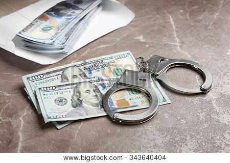Dollar Bills And Handcuffs On Brown Marble Table. Bribe Concept