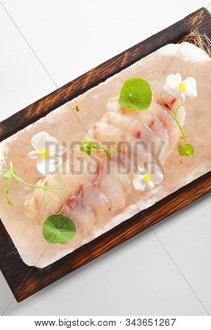 Sea perch ceviche or redfish cebiche on wood restaurant plate isolated. Raw rockfish fillet marinated in lime juice with spicy sauce, edible flowers and greens top view