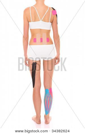 รูปภาพของด้านหลังของผู้หญิงกับ physio เทปบนส่วนต่าง ๆ ของร่างกายของเธอผ่าน backgrou สีขาว