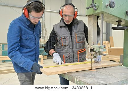 Carpenter with apprentice working in workshop
