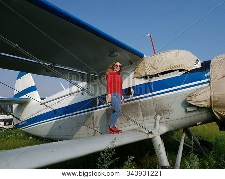 Woman Portrait In Front Of An Aircraft. Young Beautiful Woman With Red Jacket Stand In Front Of Olde