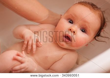 Cute Newborn Baby Bathes In The Bathroom. The Concept Of A Toddlers  Swimming