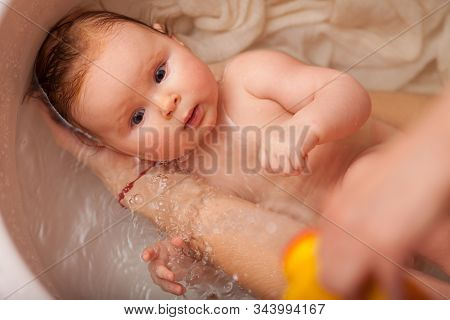 Cute Newborn Baby Bathes In The Bathroom. The Concept Of A Toddlers  Swimming