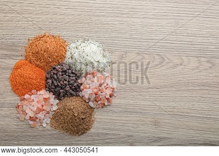 Different Kinds Of Salt On Wooden Table, Top View. Space For Text