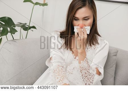 Symptoms Of Allergic Rhinitis In Women. Sick Woman In White Nightwear With A Cold Blowing Her Nose I