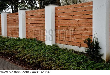 Wooden Fence Made Of Natural Planks. The Columns Are Made Of Roughly Plastered White Columns. Full F