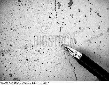 Shallow Hairline Crack In Fresh Concrete Caused By Shrinkage During Curing. Pen Used For Reference.