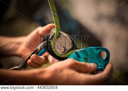 Man's Hands Operating A Rock Climbing Belaying Device
