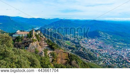 a panoramic view of the Serra de Queralt moutain, in Berga, Catalonia, Spain, highlighting the Mare de Deu de Queralt Shrine on the left and the town of Berga in the valley, on the right