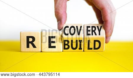 Recovery And Rebuild Symbol. Businessman Turns Cubes And Changes The Word 'recovery' To 'rebuild'. B