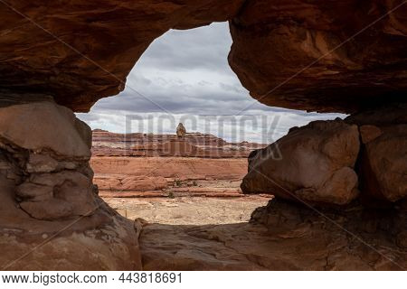 Eroded Hole In The Rock Wall Along Peekaboo Trail Frames Shaman Rock In Canyonlands