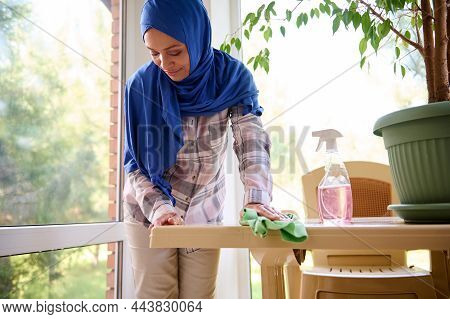 Housekeeping, Chores, Cleaning Concept. Arab Muslim Woman With Head Covered In Hijab Doing Cleaning 