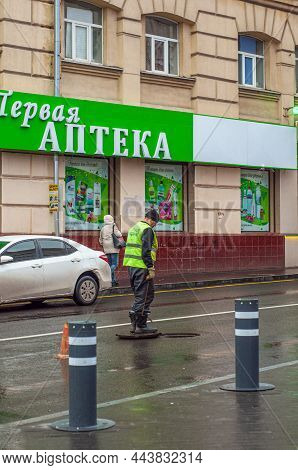 Kharkov, Ukraine. December 10. 2021. A Utility Worker In A Bright Yellow Vest Stands Near An Open Ha