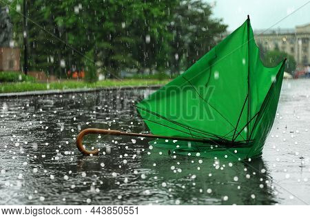 Broken Green Umbrella In Park On Rainy Day With Hail