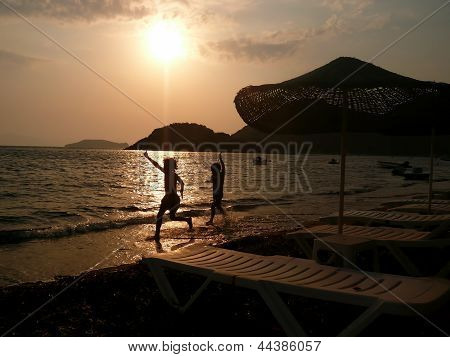 Børn der kører på stranden ved solnedgang