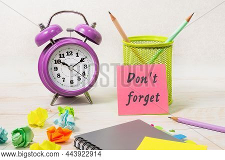 On The Desktop There Is A Bio-alarm Clock, A Pencil Holder, A Notebook. The Pink Sticker Says - Don'