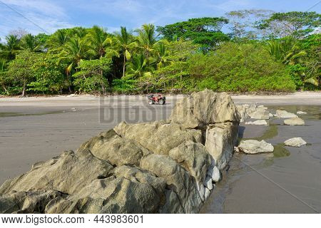 All-terrain Bike Standing On A Rocky Beach Of An Exotic Remote Island.