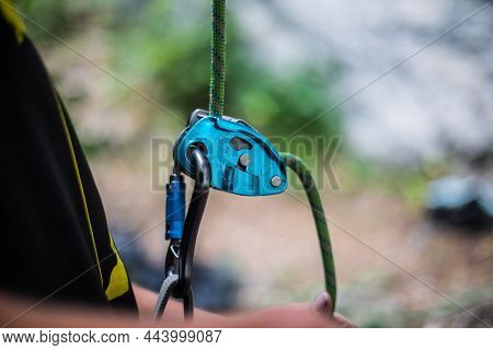 Man's Hands Operating A Rock Climbing Belaying Device