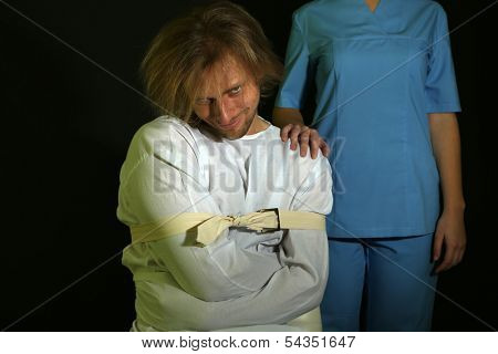 Mentally ill man in strait-jacket on black background