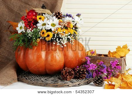 Beautiful autumn composition in pumpkin with bumps and decorative box on table on wooden background