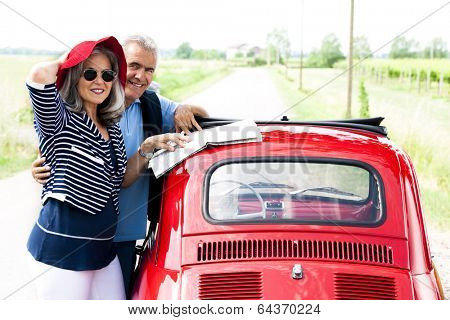 Senior couple with vintage car lookinga t a map