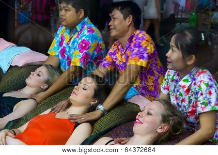 BANGKOK, THAILAND - MARCH 22: Thai masseur doing massage outdoors at the famous backpackers destination Khao San Road at night on March 22, 2014 in Bangkok, Thailand.