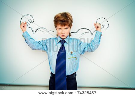Smart boy stands by the whiteboard in a classroom expressing the power of knowledge. Educational concept. Copy space.