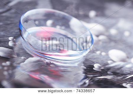 Contact lens with water drops on bright background