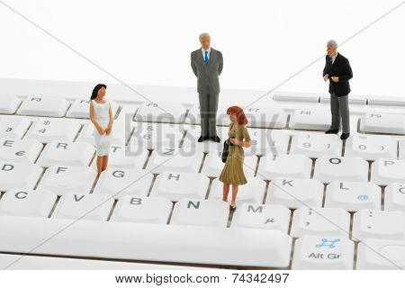 several figures of business people standing on a computer keyboard