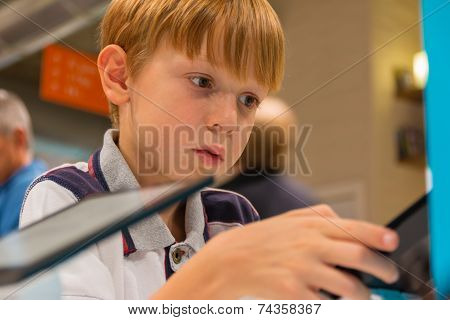 Kid (7-8 Years) Playing With Tablet Computer In A Shop