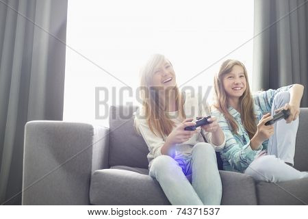 Sisters playing video games on sofa