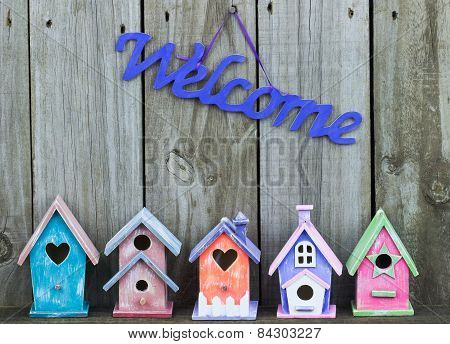 Purple welcome sign by collection of birdhouses