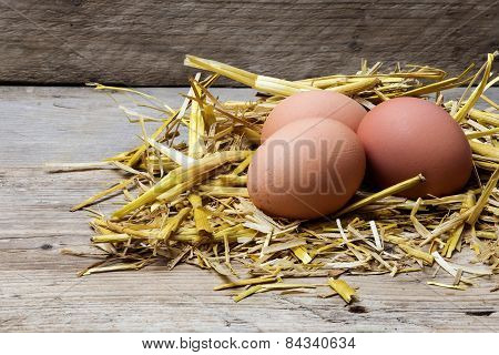 Three Eggs In A Nest Of Golden Straw On Old Wood, Copyspace