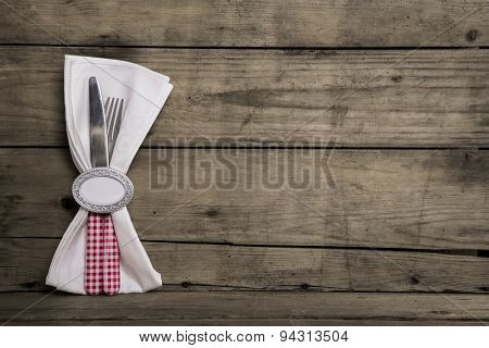 Silver cutlery in red and white checked with napkin on an old wooden background.